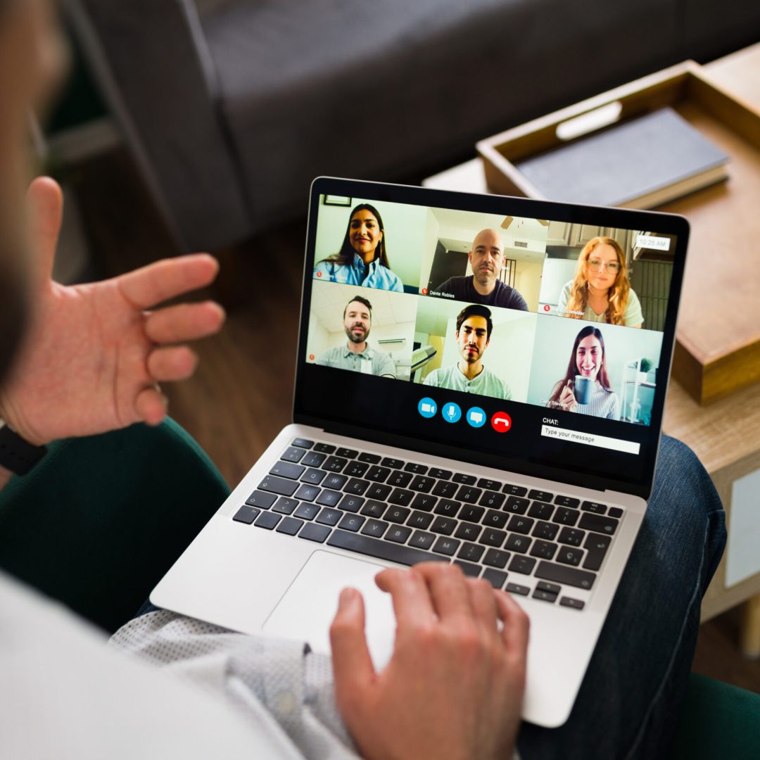 Rear view of a man having a work meeting online. Adult man talking with co-workers during a video call on his laptop